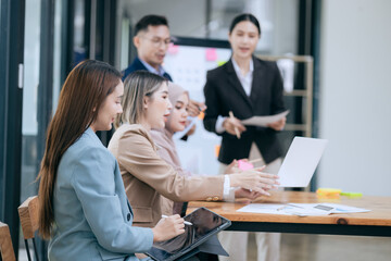 Professional business people taking part in a business meeting Discussing finances, strategies, and investing, they analyze charts on laptops. Demonstrate teamwork and effective communication.