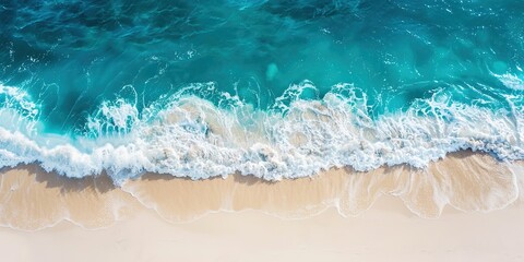 Clean ocean waves breaking on sand beach with turquoise emerald coloured water
