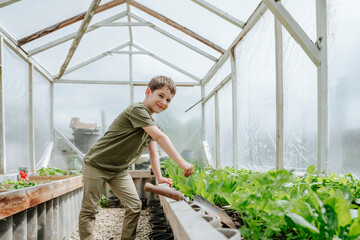 Smiling boy gardening in greenhouse