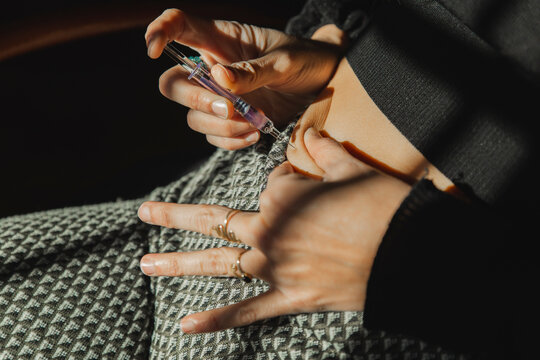 Woman injecting ovulation hormones syringe in stomach