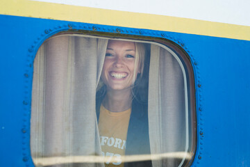 Cheerful young woman looking through airplane window