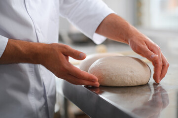 Baker kneading dough in a bakehouse or bakery