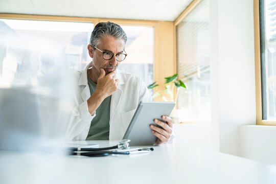 Man in lab coat using tablet PC in clinic
