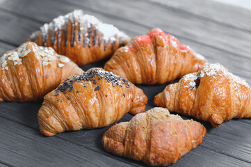 Board with tasty croissants on table, closeup. French pastry