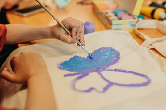 Boy coloring butterfly on bag at home