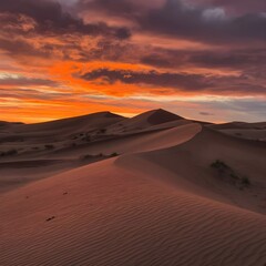 Fototapeta premium A sunset in the desert: the sand dunes are dyed a deep orange, while the sky is transformed into a canvas of orange, reddish and violet tones.