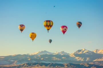 Fototapeta premium Hot Air Balloons Soaring Over Snowy Mountain Range