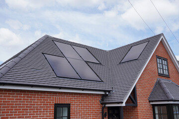 new build house with solar panels installed on roof. residential property with photovoltaic solar cells. sustainable energy source 