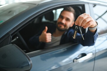 Young man is choosing a new vehicle in car dealership