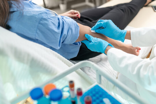 Healthcare worker drawing blood from a patient in a hospital room.