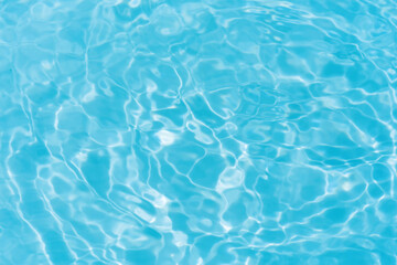 Blue water with ripples on the surface. Defocus blurred transparent blue colored clear calm water surface texture with splashes and bubbles. Water waves with shining pattern texture background.