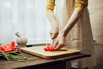 Unrecognizable man chopping bell pepper with kitchen knife in the kitchen