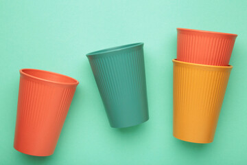 Eco plastic glass of various color on mint background. Space for text