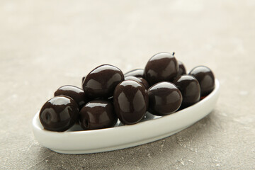 Fresh olives in white plate on grey concrete background.
