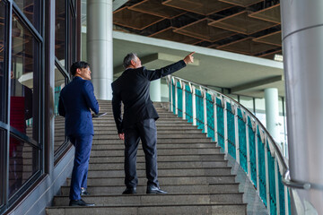 Professional Asian businessman and senior executive working and discussion business economy financial outside office building. Business people startup teamwork meeting corporate business in the city.