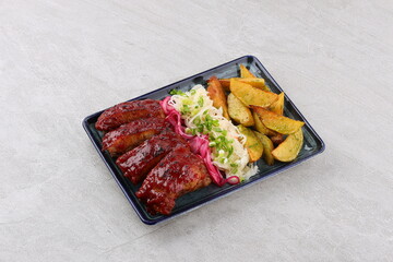Close up Gourmet Main Dish with Grilled Pork Rib and Fried Potatoes on White Plate. Served on Wooden Table.