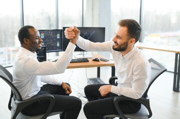 Two happy successful excited diverse traders investors giving high five celebrating successful...