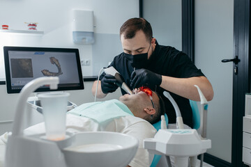Dentist scanning teeth of male patient with modern scanning 3d machine