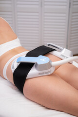 professional electrostimulation session, close up view o therapist applying EMS device on woman in...
