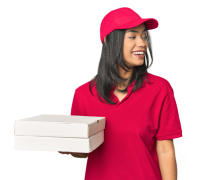 Latina delivering pizza, studio setup looks aside smiling, cheerful and pleasant.
