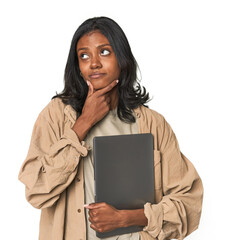 Fototapeta premium Young Indian woman studying with laptop looking sideways with doubtful and skeptical expression.