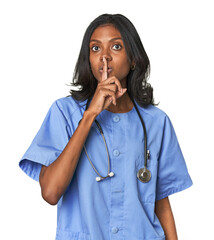 Young Indian nurse with stethoscope keeping a secret or asking for silence.