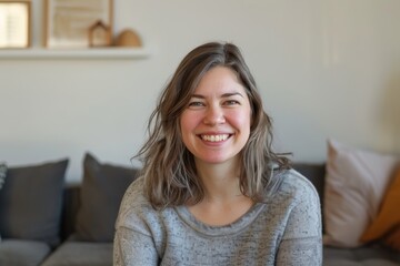 Fototapeta premium Portrait of a happy woman in her 30s smiling at the camera isolated in crisp minimalistic living room