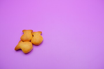 three biscuits shaped like fish isolated on a purple background