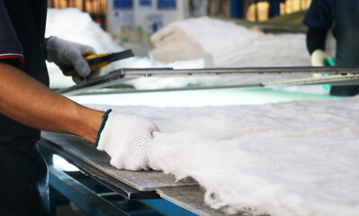Hands cutting fiberglass insulation.