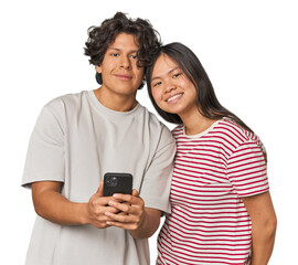 Fototapeta premium Young interracial couple using smartphone happy, smiling and cheerful.