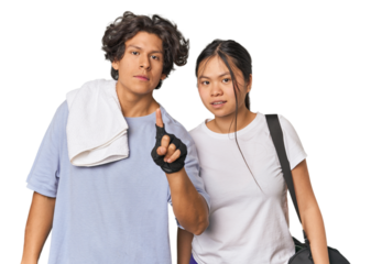 Young interracial athletic couple in studio showing number one with finger.