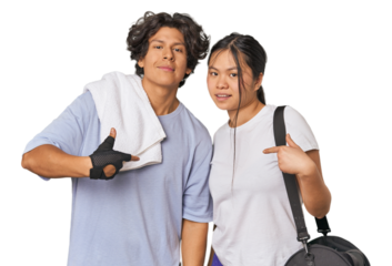 Young interracial athletic couple in studio person pointing by hand to a shirt copy space, proud and confident