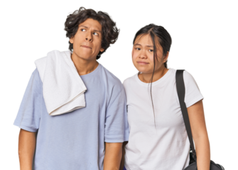 Young interracial athletic couple in studio confused, feels doubtful and unsure.