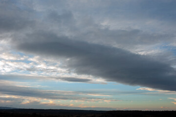 Sunrise over the field. The sun's rays fall on the plowed fields and on the forest under the mountain.