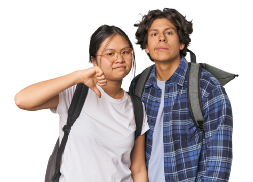 Young interracial student couple studying showing a dislike gesture, thumbs down. Disagreement concept.