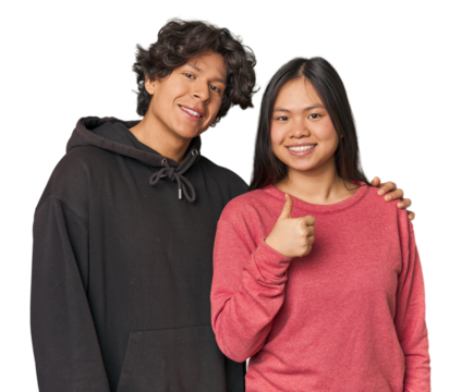 Young interracial couple in studio smiling and raising thumb up
