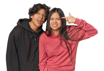 Young interracial couple in studio showing a disappointment gesture with forefinger.