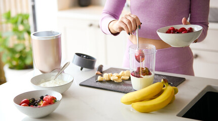 Close Up Of Woman Mixing Yoghurt And Fresh Fruit In Blender For Healthy Smoothie In Kitchen At Home