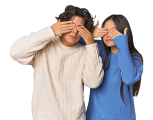 Young interracial couple in studio afraid covering eyes with hands.