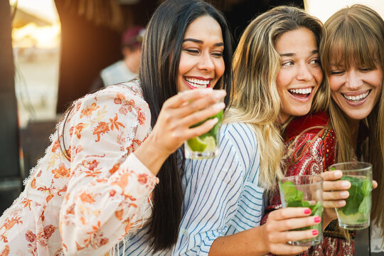 Multiracial happy women friends cheering and drinking mojitos at beach party - Summer and vacation concept - Focus on right girl face