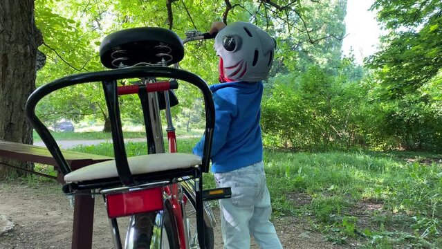 child little boy with wrench playing unscrewing nuts on bicycle in summer park - Powered by Adobe