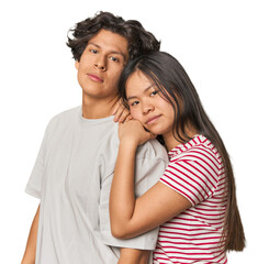 Happy multiracial couple hugging and looking at camera in studio