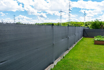 Anthracite-colored masking net placed on a mesh fence, visible vegetable boxes.