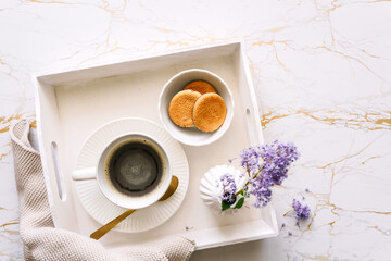 Eine Tasse Kaffee, Kekse in einer Schüssel und frische Blumen in einer Vase auf einem weißen...