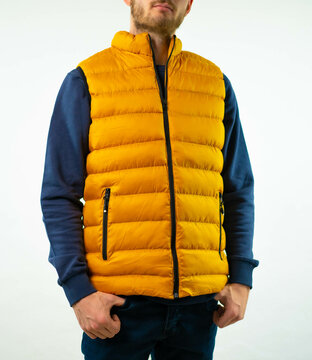 Modelo posa con un chaleco sin mangas naranja sobre una sudadera azul 