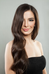 Naklejka premium Glorious young adult model woman with long healthy hairstyle, fresh shiny clear skin and makeup posing on white background. Beautiful female face close up