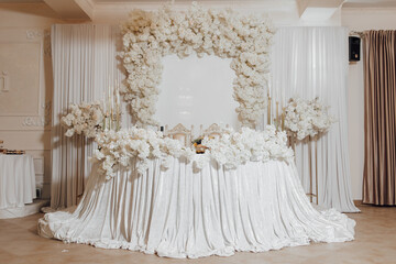 A white table with a white tablecloth and white flowers on it. The table is set for a wedding reception