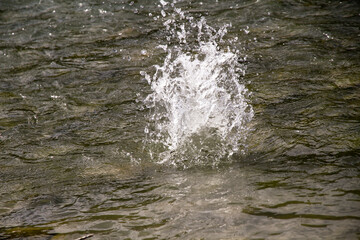 A stream of water emerges from a rock in a river landscape