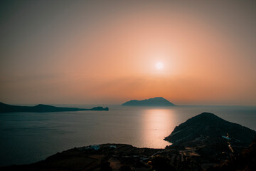 A peaceful dramatic sunset over a seascape with an island in the background