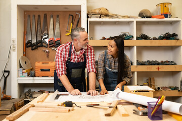 White senior man carpenter doing his work with Asian co worker woman, craft work at furniture factory and copy spcae.